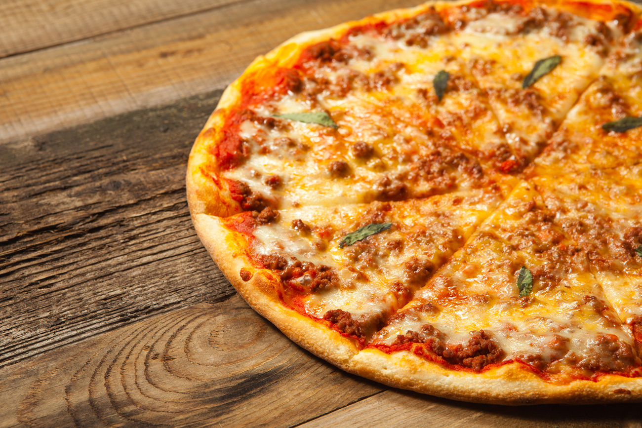 Bolognese pizza on wooden table.